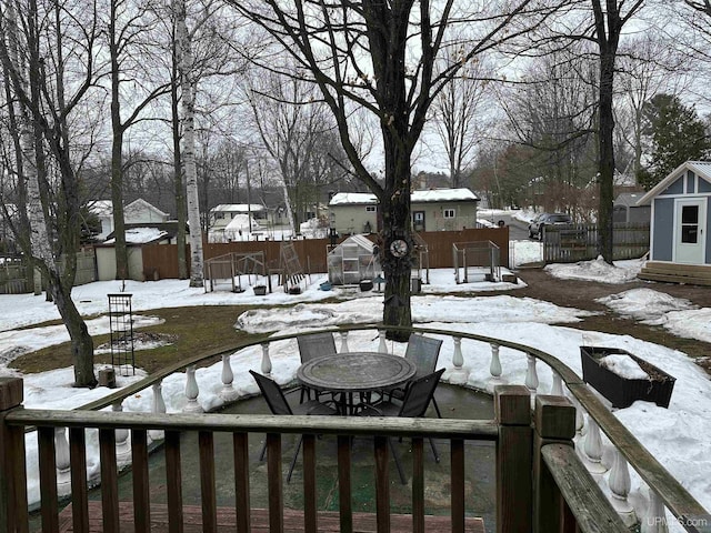 yard layered in snow with an outbuilding, a storage shed, fence, and a residential view