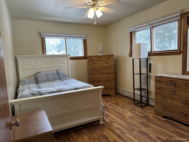 bedroom with ceiling fan, a baseboard heating unit, and dark wood-type flooring