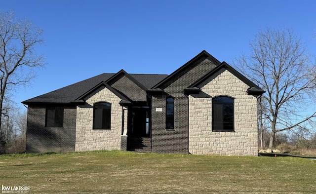 french provincial home featuring brick siding, roof with shingles, and a front yard