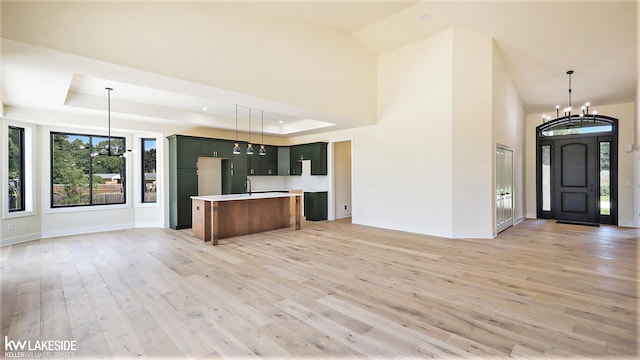 kitchen with light wood-type flooring, an inviting chandelier, a raised ceiling, and open floor plan