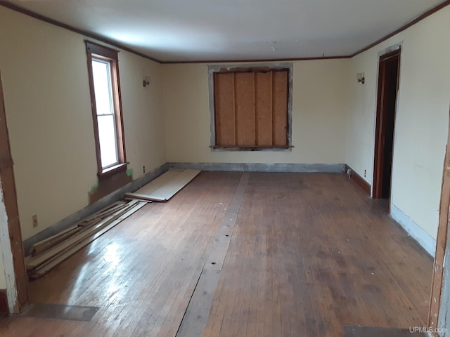 spare room with wood-type flooring, ornamental molding, and baseboards