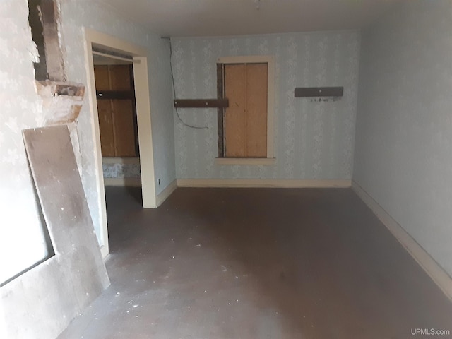 spare room featuring concrete floors and baseboards