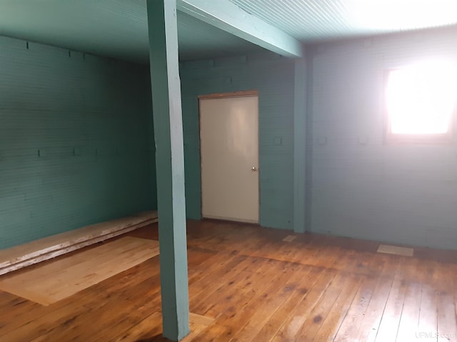 spare room with beamed ceiling and hardwood / wood-style flooring