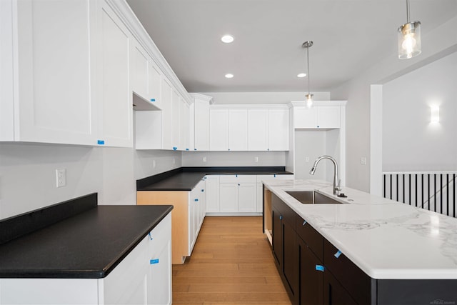 kitchen featuring light wood finished floors, recessed lighting, hanging light fixtures, a sink, and an island with sink