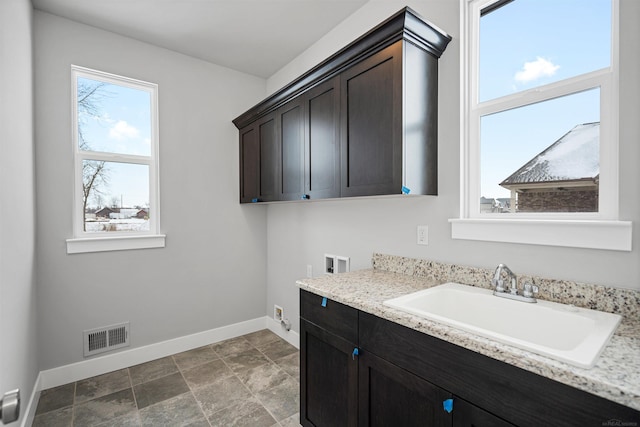 laundry room featuring hookup for a washing machine, cabinet space, visible vents, a sink, and baseboards