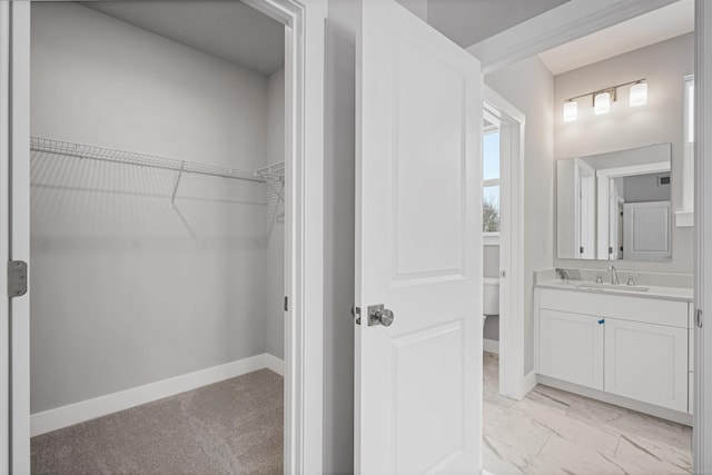 bathroom with toilet, a spacious closet, vanity, and baseboards