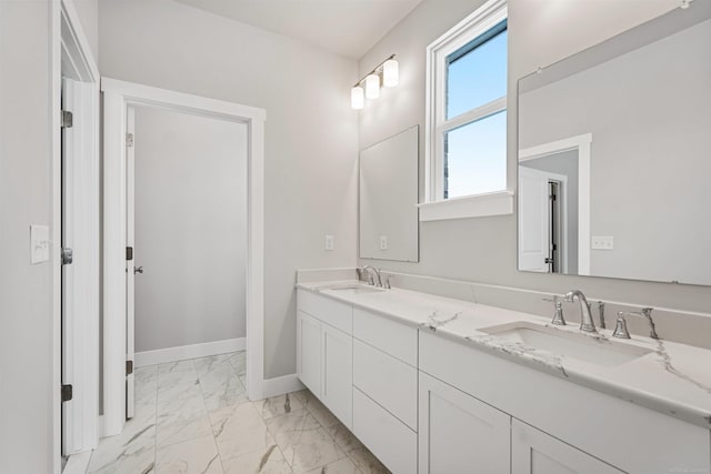 full bathroom with marble finish floor, double vanity, a sink, and baseboards