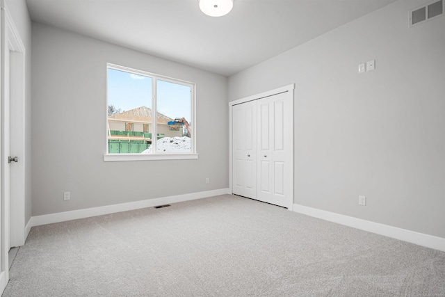 unfurnished bedroom featuring baseboards, visible vents, and light colored carpet