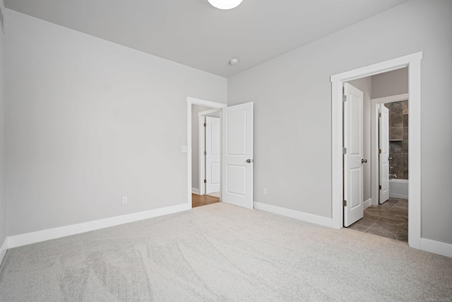 unfurnished bedroom with connected bathroom, baseboards, and carpet flooring