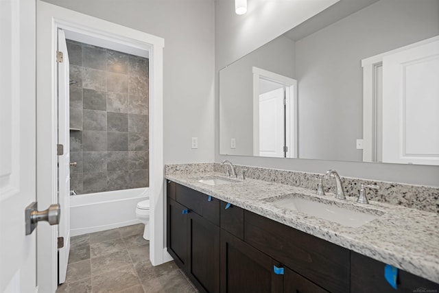 bathroom with double vanity, shower / tub combination, a sink, and toilet