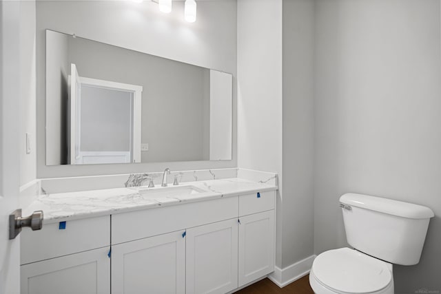 bathroom with toilet, baseboards, and vanity