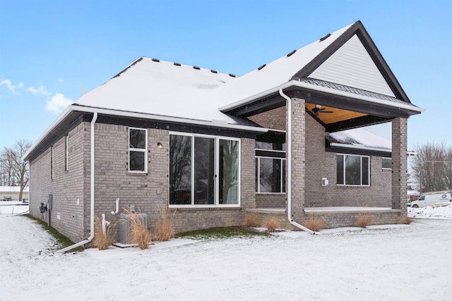 snow covered back of property featuring brick siding