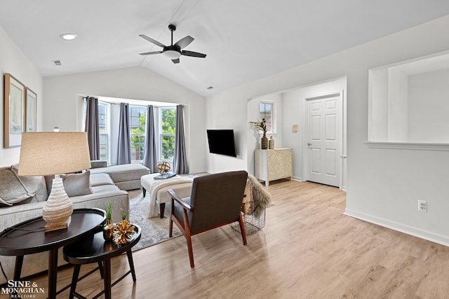 living area with vaulted ceiling, ceiling fan, light wood finished floors, and baseboards