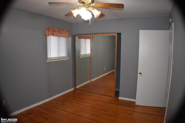 unfurnished bedroom with ceiling fan, a closet, baseboards, and wood finished floors