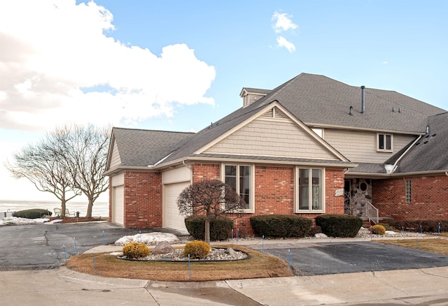 view of front facade featuring a garage, brick siding, driveway, and roof with shingles