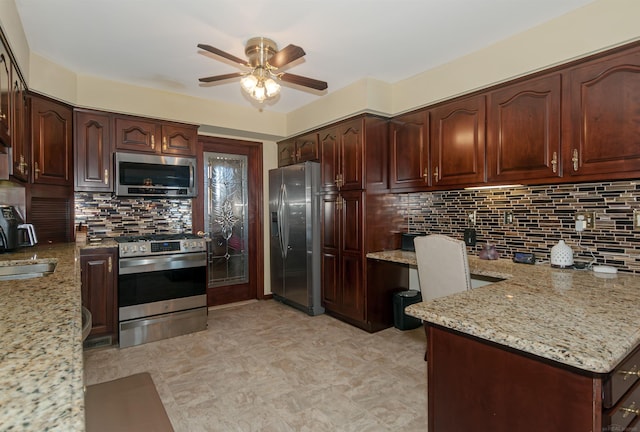 kitchen with built in desk, backsplash, appliances with stainless steel finishes, ceiling fan, and light stone countertops