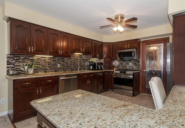 kitchen with ceiling fan, stainless steel appliances, a sink, backsplash, and light stone countertops