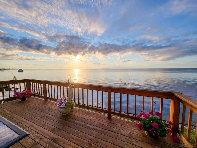 deck at dusk featuring a water view