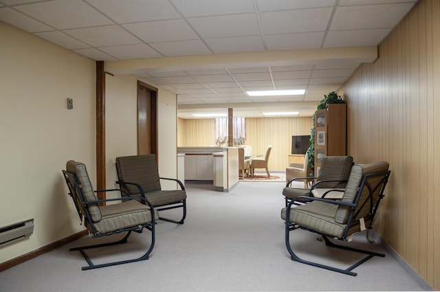 living area featuring carpet, wooden walls, baseboards, and a baseboard radiator