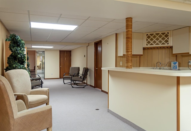 interior space featuring light countertops, a drop ceiling, carpet flooring, and baseboards