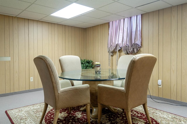 dining space with a paneled ceiling and wooden walls