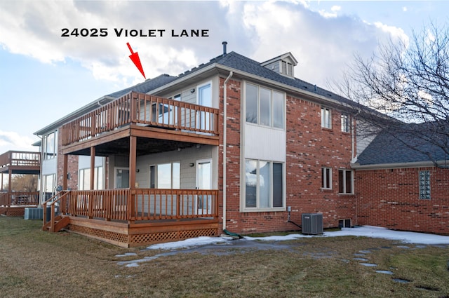 back of house with central air condition unit, brick siding, a shingled roof, and a yard