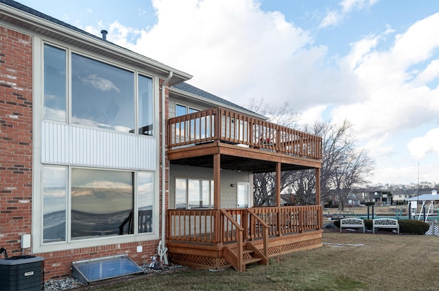 rear view of house featuring brick siding, a lawn, a deck, and central air condition unit