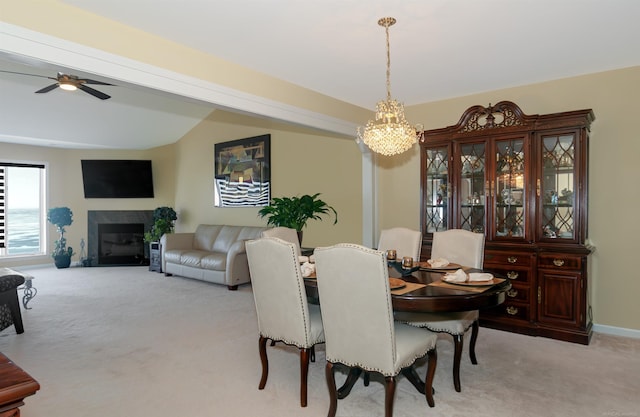 dining area with a fireplace with flush hearth, lofted ceiling, light carpet, and a ceiling fan