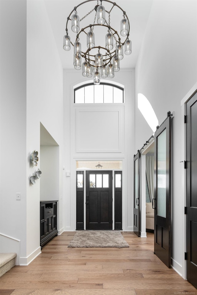 entryway with light wood finished floors, a barn door, plenty of natural light, and a high ceiling