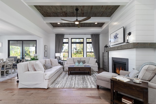 living room featuring a healthy amount of sunlight, hardwood / wood-style flooring, wood ceiling, and a glass covered fireplace