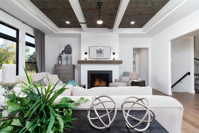 living area featuring wood ceiling, a large fireplace, beam ceiling, and wood finished floors