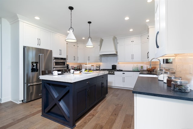 kitchen with stainless steel appliances, tasteful backsplash, white cabinetry, a sink, and premium range hood