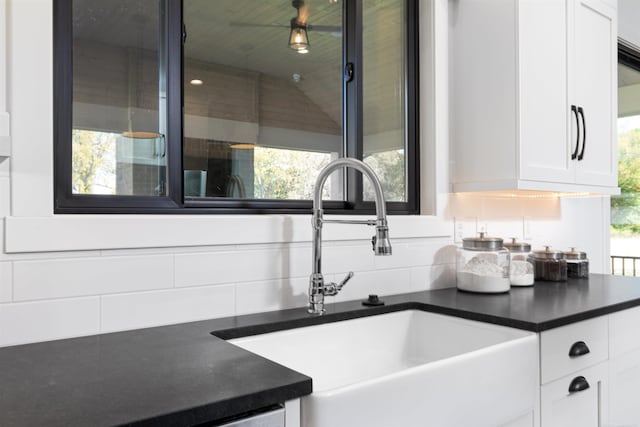 interior space with a wealth of natural light, dark countertops, white cabinetry, and a sink