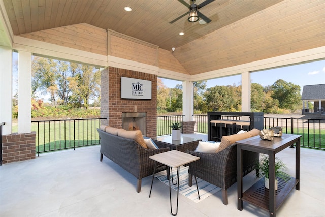 view of patio / terrace with ceiling fan and an outdoor living space with a fireplace