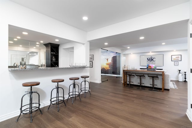 kitchen with recessed lighting, baseboards, a kitchen bar, and wood finished floors