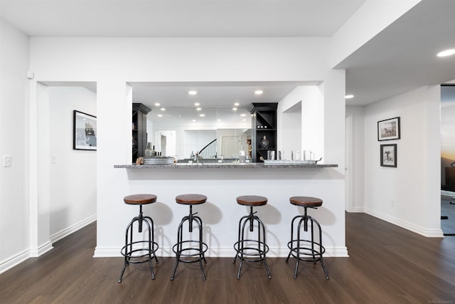 kitchen with dark wood-style floors, recessed lighting, baseboards, and a breakfast bar area