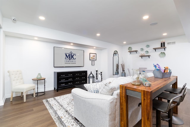 living area with baseboards, wood finished floors, visible vents, and recessed lighting