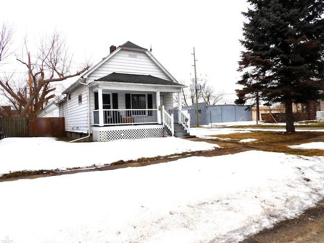 shotgun-style home with a chimney, fence, and a porch