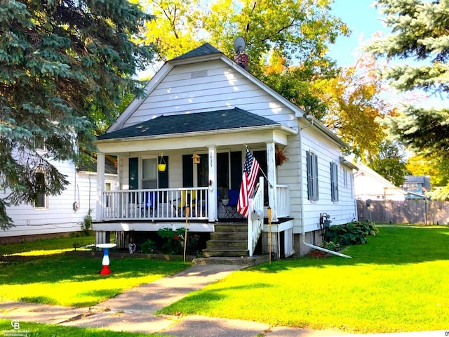 bungalow featuring a porch, roof with shingles, fence, and a front lawn