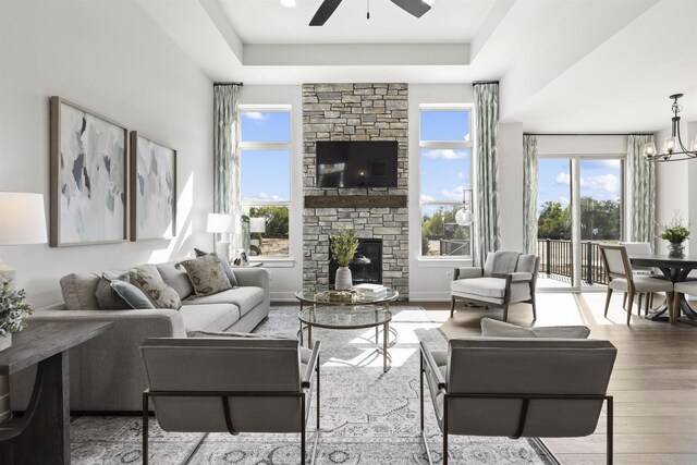 3888 Chatham Pl Unit 99, Brighton, MI 48114 - living room with a tray ceiling, a fireplace, wood finished floors, baseboards, and ceiling fan with notable chandelier