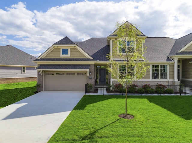 craftsman-style home with driveway, a garage, a shingled roof, fence, and a front lawn