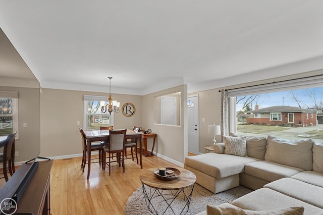 living room featuring a chandelier, light wood-style flooring, and baseboards