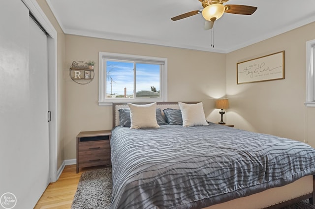 bedroom with crown molding, a closet, a ceiling fan, wood finished floors, and baseboards