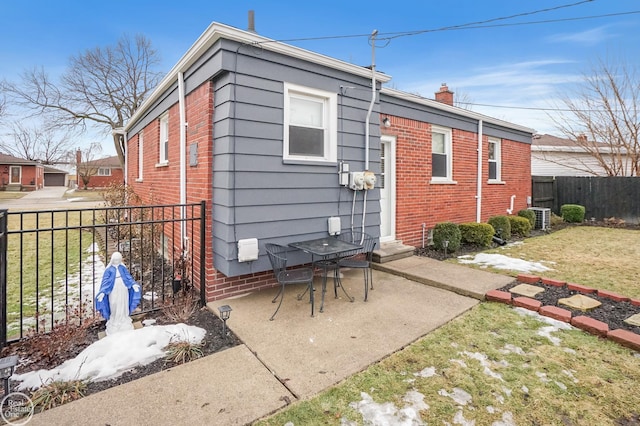 back of property featuring a chimney, fence, a yard, a patio area, and brick siding