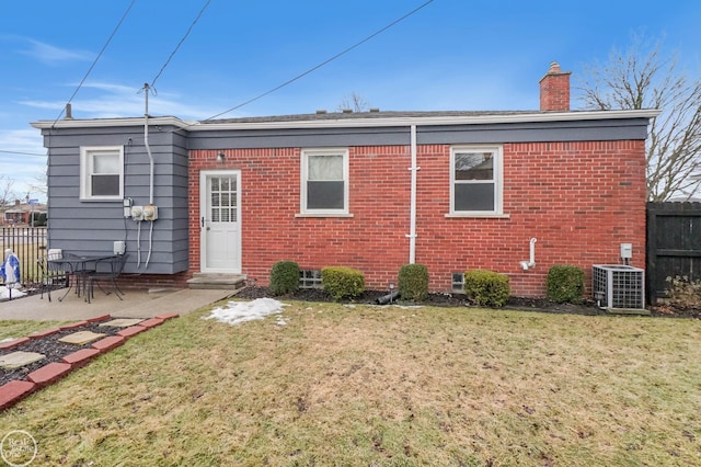 back of property with central AC unit, a chimney, fence, and brick siding