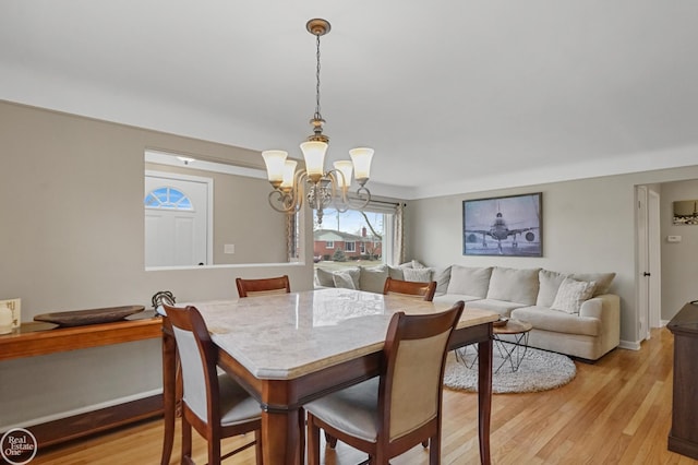 dining room featuring a chandelier, light wood-style flooring, and baseboards