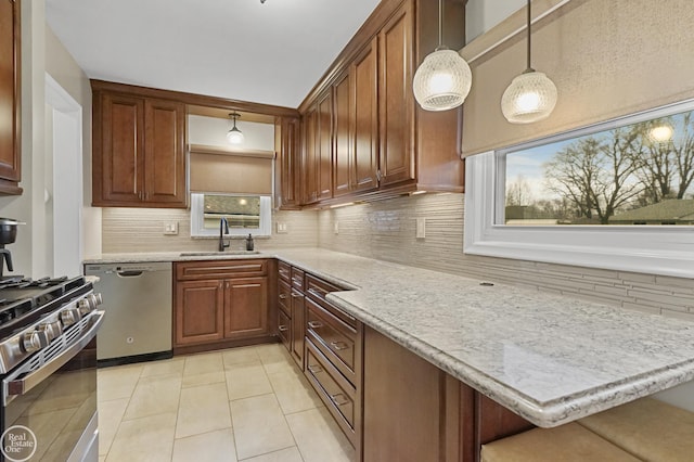 kitchen featuring tasteful backsplash, appliances with stainless steel finishes, hanging light fixtures, a sink, and light tile patterned flooring