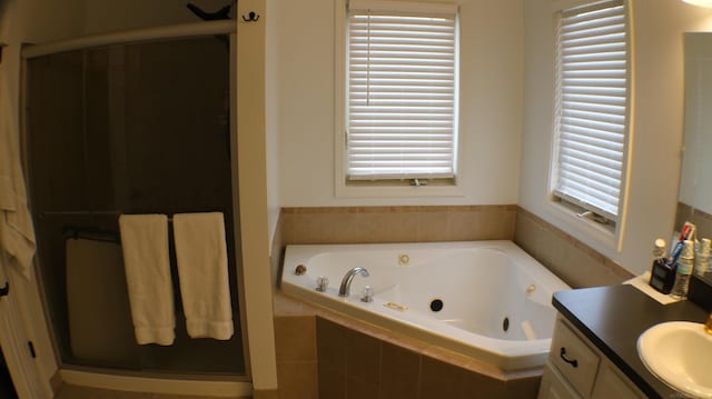 bathroom featuring a stall shower, a jetted tub, and vanity