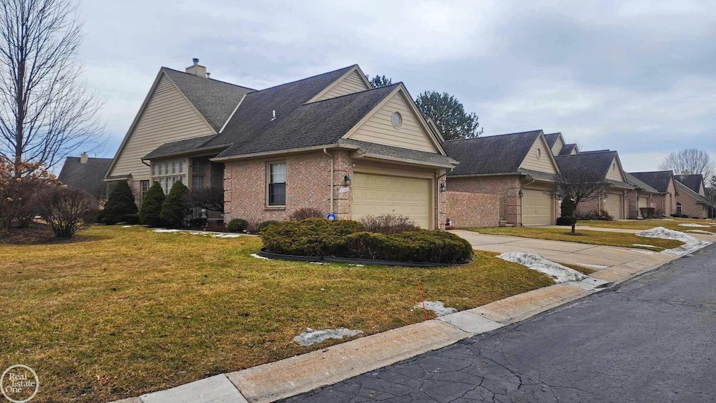 view of side of home with a garage, brick siding, driveway, a yard, and a chimney