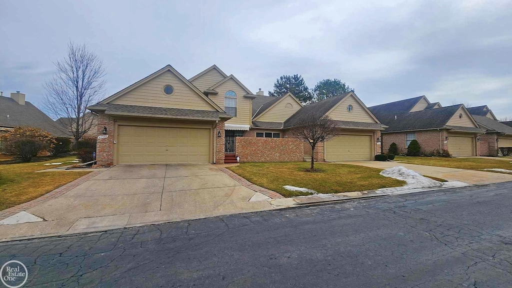 view of front of property featuring a garage, a front yard, concrete driveway, and brick siding